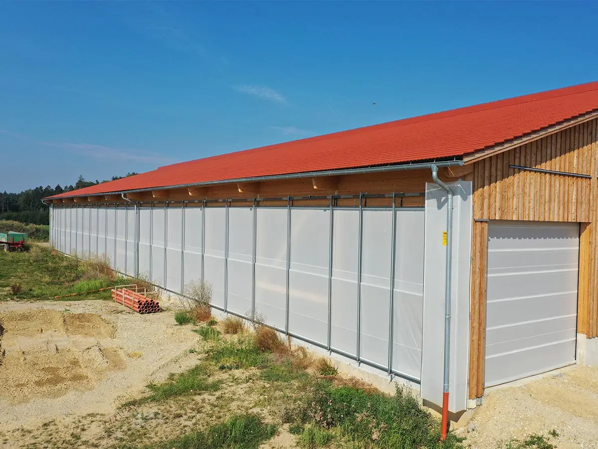 Stalltore und Windschutzsysteme an einem Stallgebäude
